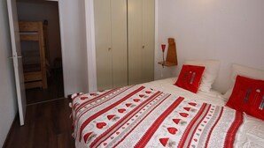 Un dormitorio con cama, armario y mesita de noche con lámpara.