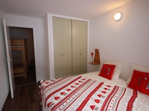 Une chambre à coucher avec un lit, une armoire et une table de chevet avec une lampe.