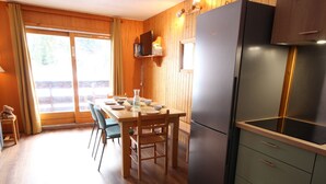 Una cocina compacta con refrigerador, gabinetes de madera y una mesa de comedor con sillas.