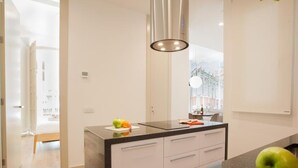 Een moderne keuken met een centraal eiland, witte kasten en een groot raam voor natuurlijk licht.