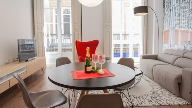 Een moderne woonkamer met een ronde eettafel, een rode stoel en een bank.