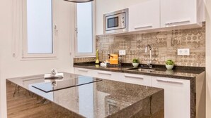 Een moderne keuken met een centraal eiland, witte kastjes, een magnetron en een decoratieve achterwand.