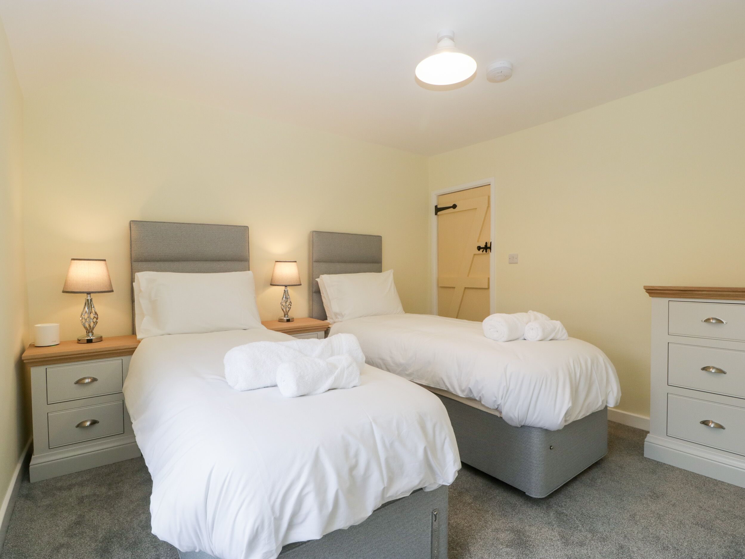 A double room with two beds, bedside tables with lamps, a wardrobe, and a door.