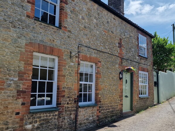A stone building with multiple windows and a green door. - Granary Cottage (Warminster)