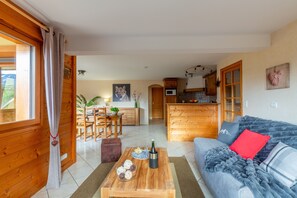 A cozy living room with a sofa, a wooden coffee table, and a dining area with a table and chairs.
