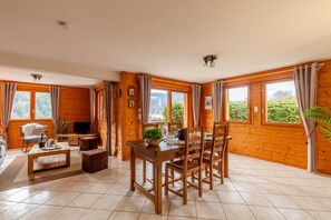 L’intérieur d’un chalet en bois comprend une table à manger, des chaises, un canapé et un téléviseur.