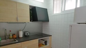 Eine Küche mit Holzausstattung, einer schwarzen Mikrowelle, einem Spülbecken mit Armatur und einem weißen Kühlschrank.