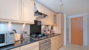 A modern kitchen with stainless steel appliances, wooden cabinets, and a tiled floor. - Riverview-2br-sleeps4-citycentre-parking-fastwifi (Aberdeen)