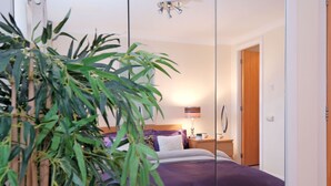 A bedroom with a bed, bedside table, lamp, and a potted plant. - Riverview-2br-sleeps4-citycentre-parking-fastwifi (Aberdeen)