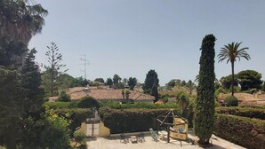 A swimming pool with a tiled deck, surrounded by greenery and a view of residential buildings. - Beachfront Estepona Apartment with Pool, Terrace & Free Parking (Estepona)