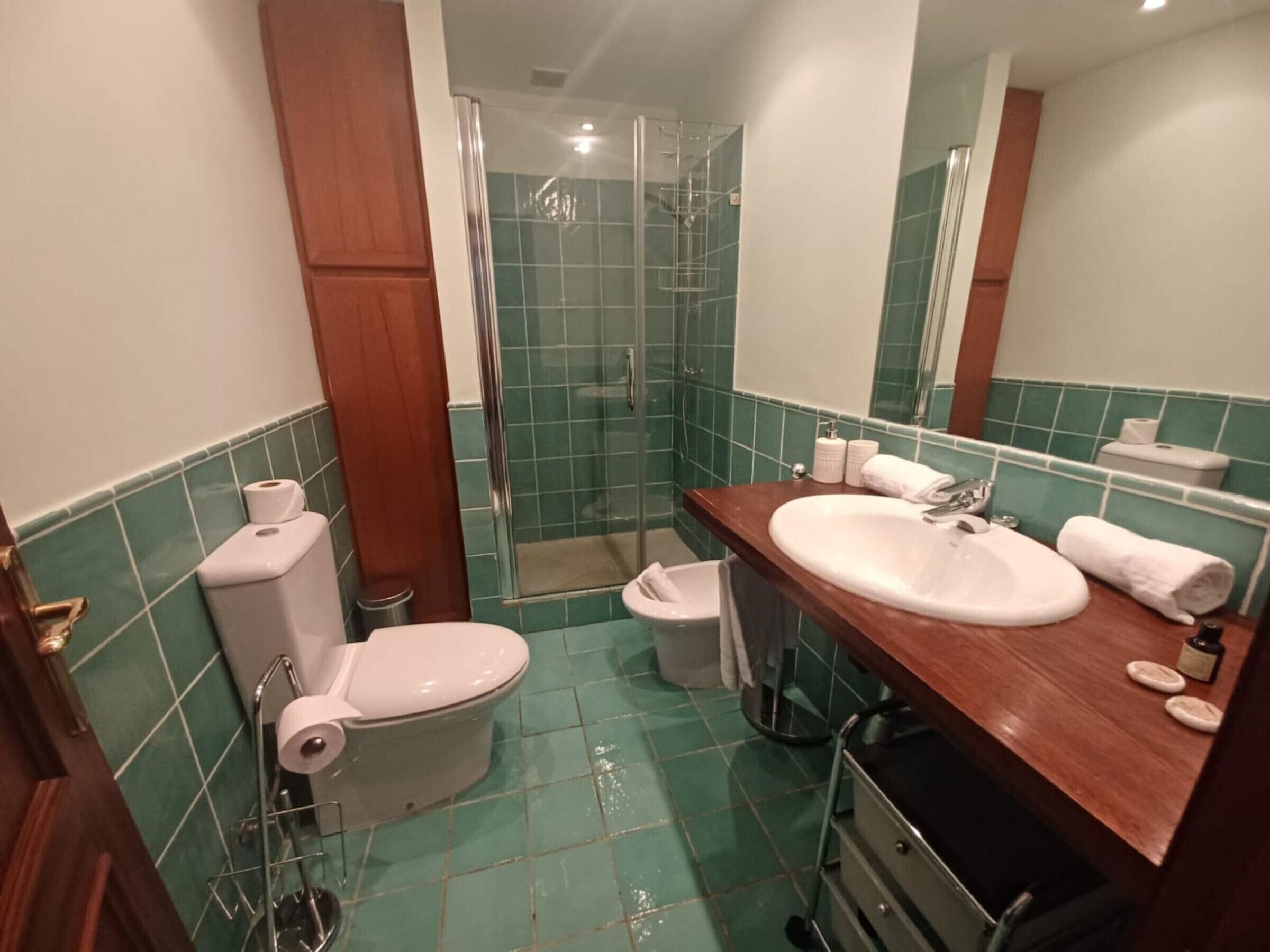 Ein Badezimmer mit Toilette, Bidet und Waschbecken mit Spiegel.