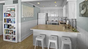 A compact kitchen with white cabinetry, a central island with bar stools, a microwave, stove, and a coffee maker. - Commodores Retreat - 101 1 Bedroom Condo by RedAwning (Santa Rosa Beach)