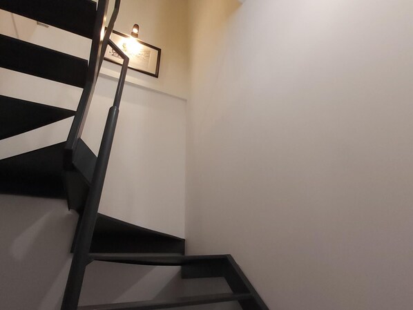 Un escalier avec des rampes noires et un tableau encadré accroché au mur.