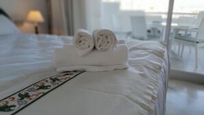 A neatly made bed with rolled towels and a decorative pillow.