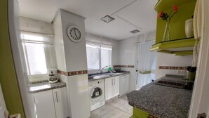 A kitchen with white cabinets, a clock, a washing machine, and a sink.