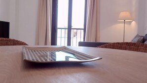 Um quarto com uma mesa de madeira, um sofá, uma luminária e uma janela com cortinas.