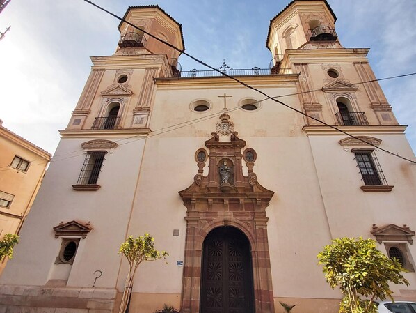 A church with a central entrance, two bell towers, and a statue above the door.