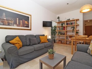 Ein modernes Wohnzimmer mit einem grauen Sofa, einem kleinen Tisch und einem Bücherregal.