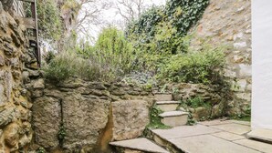 A stone staircase leading up to a stone wall with greenery growing over it. - Foxden (Sherborne)