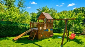A wooden play structure with a slide and swing set in a grassy yard. - Rustic Cottage With Heated Pool (Velika Gorica)