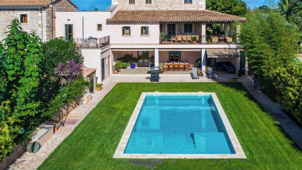 A two-story house with a swimming pool in the front yard.