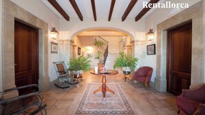 A spacious lobby with a central round table, two rocking chairs, and a staircase leading to upper floors.