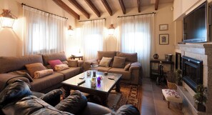 Ein geräumiges Wohnzimmer mit Kamin, Fernseher und einer gemütlichen Sitzecke.