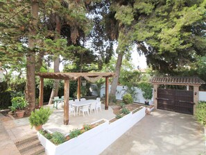 Eine Terrasse mit einer Pergola, Sitzgelegenheiten im Freien und einem kleinen Gartenbereich.