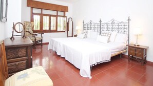 A bedroom with a large bed, a wooden chair, a nightstand, and a window with wooden shutters. - Luxury Villa with Private Pool, Near Beach and Golf (Málaga)