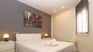 Camera d'albergo con un letto grande, due comodini con lampade, un quadro al muro e una finestra con tende.