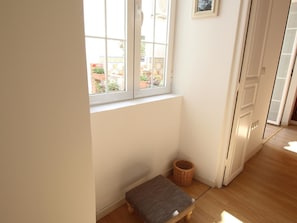 A corner room with a window, a small bench, and a wicker basket.