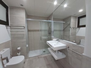 Une salle de bain moderne avec une douche à parois de verre, un lavabo blanc et des toilettes.