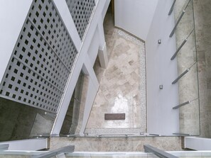 A modern interior with geometric patterns, a central stone wall, and a glass railing.