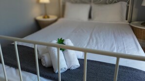 Een net opgemaakt bed met witte lakens en een klein groene plantje op de kussens.