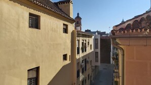 Een smalle steeg tussen gebouwen met traditionele architectuur, met balkons en een heldere lucht.
