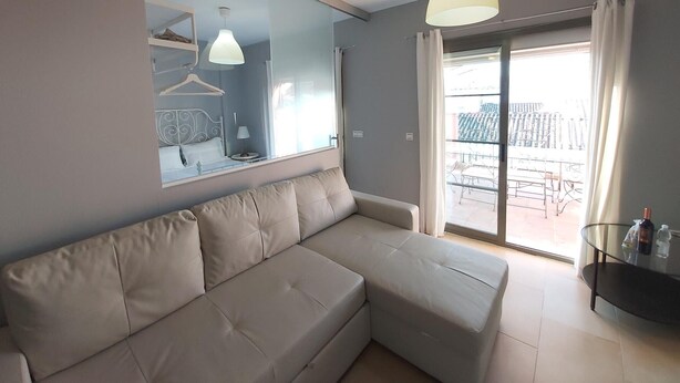 Een moderne woonkamer met een beige hoekbank, een grote spiegel en een balkon met een glazen balustrade.