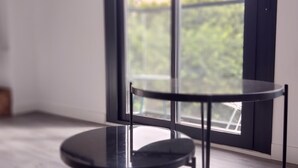 A modern room with a round black table and a chair, large windows with a view of greenery outside. - Bright 1BR Corner Apt, 3 Balconies, Central Málaga - Ideal for Work & Leisure (Málaga)