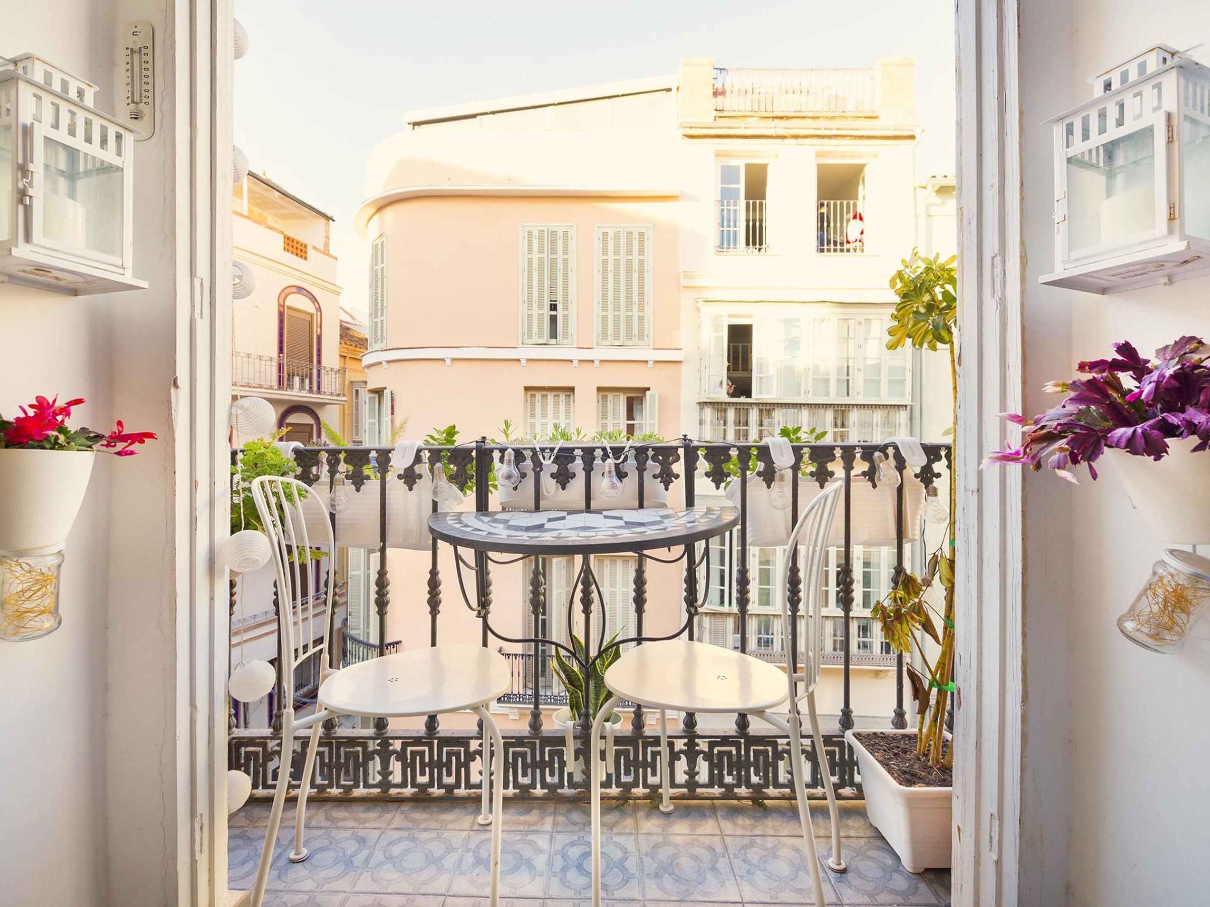 A balcony with two chairs, a small table, and potted plants.