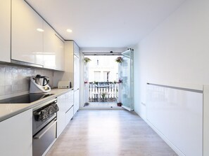 A narrow, modern kitchen with white cabinetry, a built-in oven, and a stainless steel range hood. - Modern Apartment with Balcony in Central Málaga for 4 Guests (Málaga)