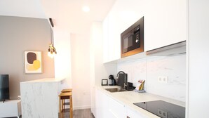 Una cucina moderna con forno a microonde, fornello e lavello integrati. Si nota un piccolo sgabello di legno e un quadro appeso al muro.
