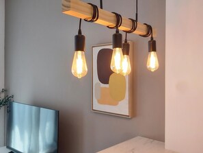 Un interior moderno con estructura de techo de madera, luces colgantes, una obra de arte enmarcada y un televisor de pantalla plana.