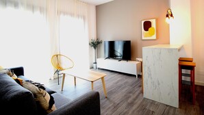 Un soggiorno moderno con un divano, una TV, un tavolino e una pianta.