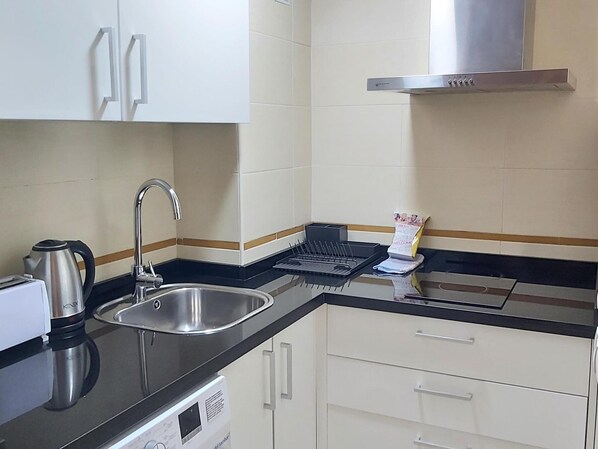 Una cocina moderna con un lavamanos de acero inoxidable, un hervidor, un tostador y una cafetera.