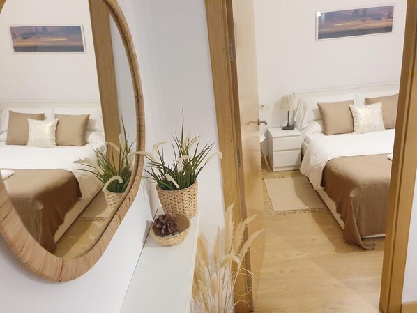 Una habitación de hotel con un espejo grande, dos camas, mesitas de noche y plantas decorativas.