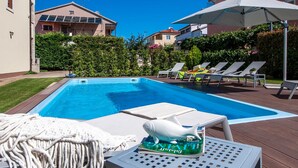 Ein Schwimmbecken mit Liegestühlen und einem Tisch mit einem Buch.