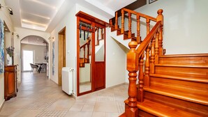Ein geräumiger Flur mit einer Holztreppe, die zu einer oberen Etage führt. Im Hintergrund ist ein Essbereich erkennbar.