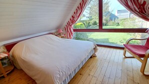Ein Schlafzimmer mit großem Fenster, einem Bett, einem Sessel und einem kleinen Tisch.