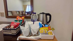 A hotel room with a dining table set with snacks, a kettle, and a tray with a checkered basket. - Welcome Hotel Islamabad (Islamabad)