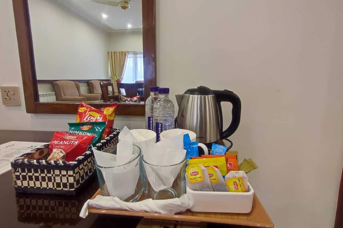 A hotel room with a dining table set with snacks, a kettle, and a tray with a checkered basket.