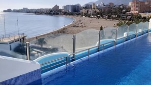 A hotel with a pool overlooking a beach and a mountain in the background.